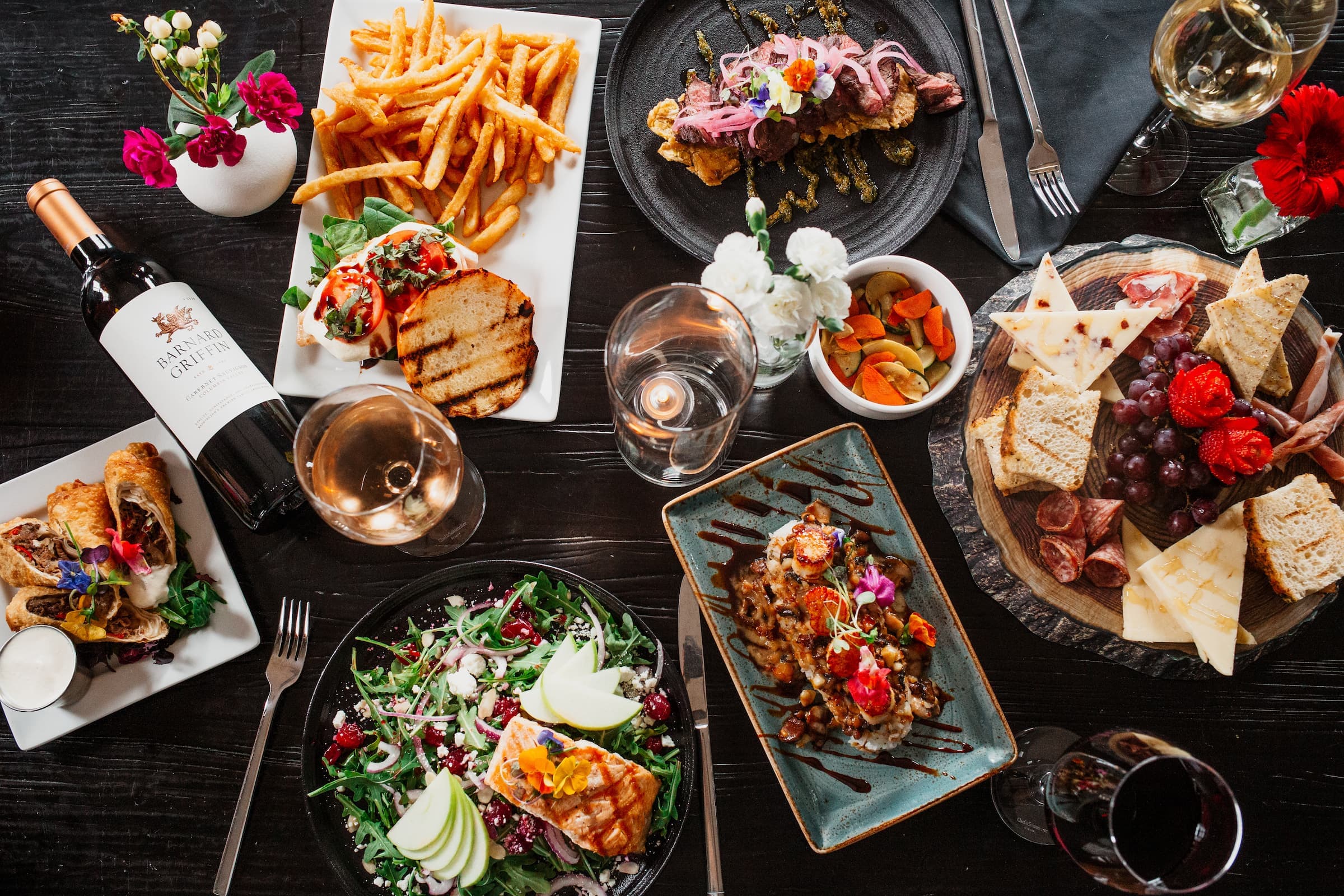 Overhead spread of plated dishes, wines, and charcuterie at Cork Wine & Tapas